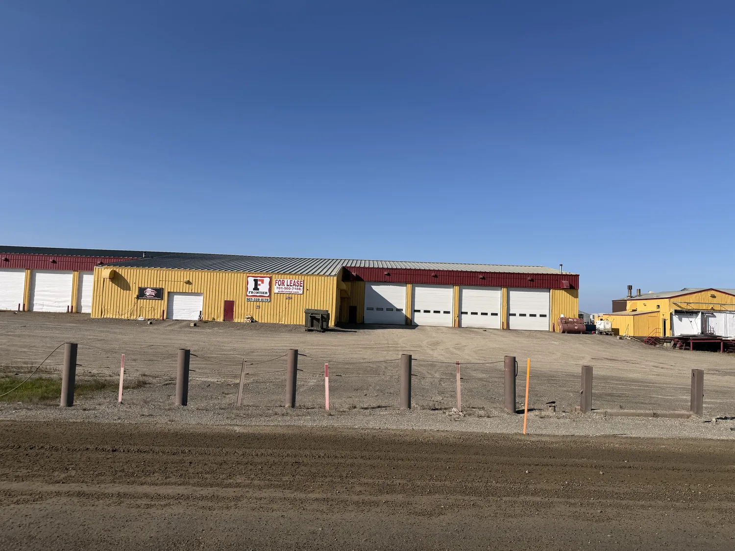 Frontier main shop with red roof, white service-bay doors, and the Frontier sign under a clear blue sky